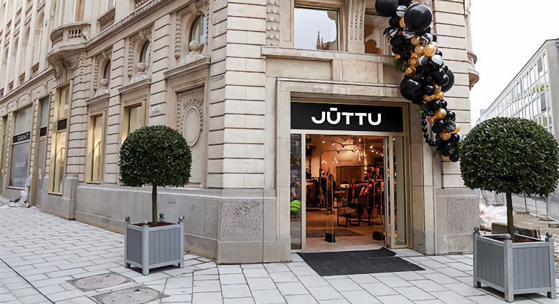 A stylish exterior shot of Juttu's storefront with elegant architecture, neatly manicured topiary, and festive balloons adorning the entrance.